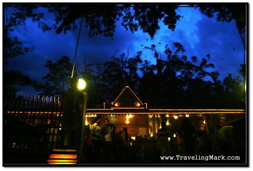 Busy Entrance to Preah Ang Chek Preah Ang Chorm Shrine with Flying Fox Bats Hovering Against Dark Sky Above