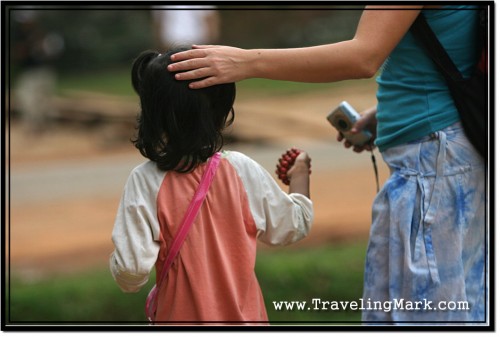 Photo: Little Girl Tout Trying to Sell Bracelets and Postcards to a Foreigner at Banteay Kdei, Angkor
