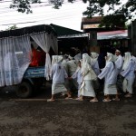 Monks Inside a Truck with Body of Deceased Followed by Immediate Family